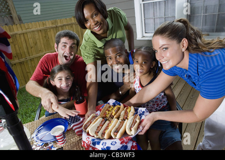 Due famiglie su backyard patio godendo un cookout il 4 luglio Foto Stock