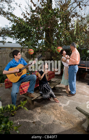 Una famiglia Mexican-American la riproduzione di musica e danza nel cortile di casa loro Foto Stock