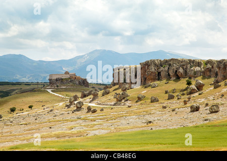 Lava vulcanica del terreno di cenere con la vecchia chiesa su di una collina e la gamma della montagna di Cappadocia Anatolia in Turchia con rottura sun ombra Foto Stock