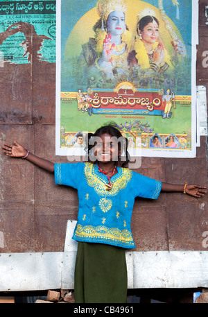 Povero indiano mendicante nomadi ragazza in piedi di fronte a un indian Rama movie poster su una capanna. Andhra Pradesh, India Foto Stock