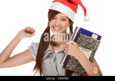 Asian schoolgirl indossando red Santa Claus hat holding composizione prenota e notebook Foto Stock