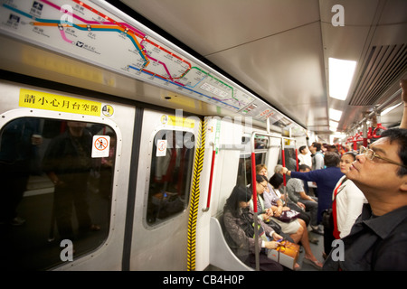 Maschio passeggeri asiatici guardando la mappa della metropolitana MTR sul treno a Kowloon hong kong cina Foto Stock