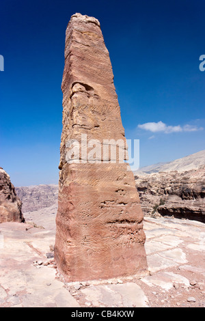 Un antico obelisco situato sulla montagna sopra antica Petra nel sole di mezzogiorno con un profondo cielo blu sullo sfondo Foto Stock