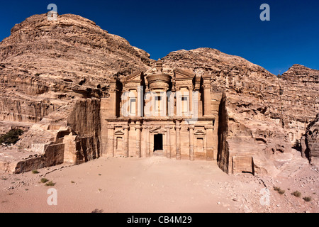 Vista in elevazione del Deir / monastero di Petra con un profondo cielo blu di sfondo e sabbie del deserto di fronte Foto Stock