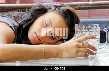 Giovane donna addormentata all'aperto su pub la terrazza dopo aver bevuto troppa birra. Foto Stock