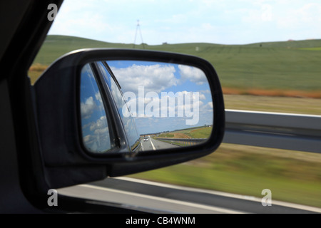 Riflettendo su strada nella veduta laterale specchio di una automobile Foto Stock