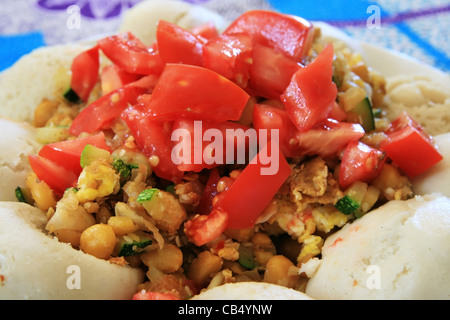 Piastra di ceci e zucchine curry circondato da iddly con pomodori freschi sulla parte superiore Foto Stock