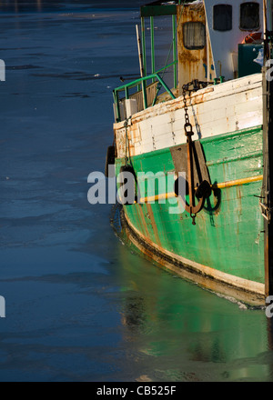 Un verde e bianco barca da pesca circondata da ghiaccio nel porto di Whitehaven, Cumbria, Inghilterra. Foto Stock