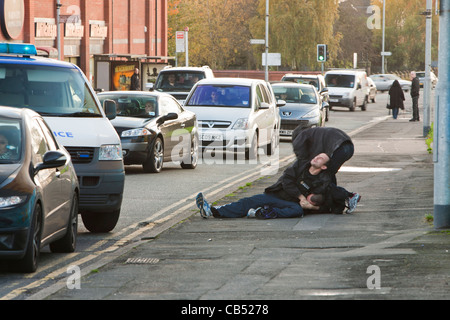 La polizia di affrontare un negozio lifter a Manchester e combattiamo lui a terra. Foto Stock