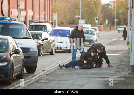 La polizia di affrontare un negozio lifter a Manchester e combattiamo lui a terra. Foto Stock