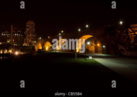 Arco in pietra Bridge di notte sotto le luci e il Mulino di rovine della città nel centro di Minneapolis Minnesota Foto Stock