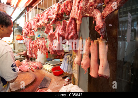 Le carni di suini compresi i piedi appeso in una delle macellerie stallo in un mercato all'aperto in Mong Kok distretto di Kowloon hong kong cina della RAS di Hong Kong Foto Stock