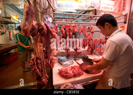 Macellaio di tritare la carne in una macelleria stallo in un mercato all'aperto in Mong Kok distretto di Kowloon hong kong cina della RAS di Hong Kong Foto Stock