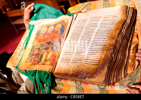 Una cappella custode visualizza un antico manoscritto illuminato presso la nuova chiesa di Santa Maria di Sion in Aksum, Nord dell'Etiopia. Foto Stock
