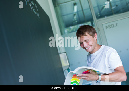 Bello studente di college per risolvere un problema di matematica durante le lezioni di matematica di fronte la blackboard/lavagna (toni di colore immagine) Foto Stock