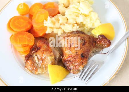 Un elevato angolo di visione di cosce di pollo, marinaded in succo di limone e le erbe aromatiche e arrostito, servita con purè di patate e carote Foto Stock