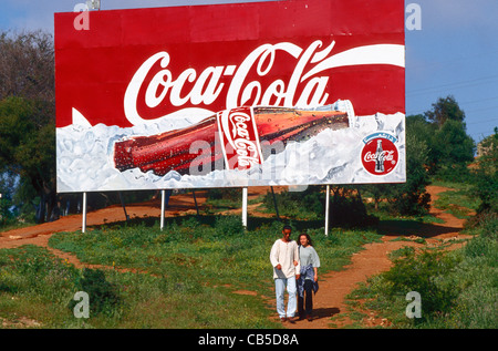 Un giovane a piedi passato un banner pubblicitari Coca cola ad Algeri, Algeria. Foto Stock