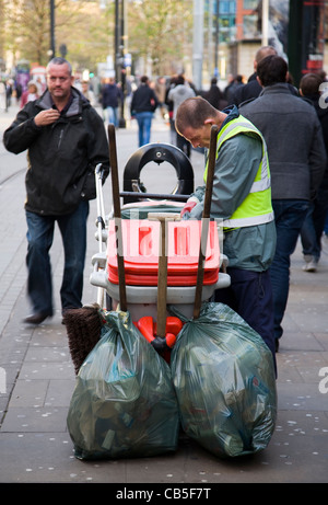 Pulitore di via durante le vendite di Natale e la festa di acquirenti acquistano merci in Piccadilly Manchester, Regno Unito Foto Stock