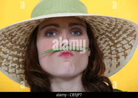 La donna il bilanciamento di un fagiolo verde tra le sue labbra e il suo naso Foto Stock