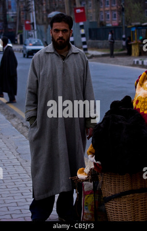 Un uomo Kashmiri in stoffa tradizionale che vende le cose sul sentiero intorno al lago di dal, Srinagar, Kashmir, India Foto Stock