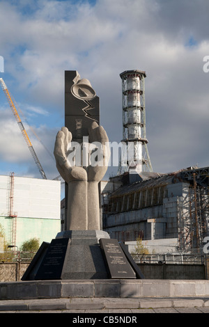 Memoriale per i liquidatori di Chernobyl con reattore numero 4 in background, la centrale di Cernobyl in Ucraina Foto Stock