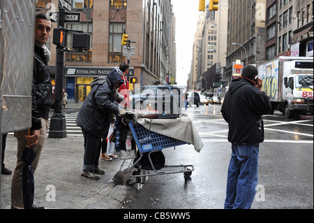 Senzatetto maschio con carrello della spesa pieno di cose a piedi nel traffico Manhattan New York New York STATI UNITI D'AMERICA Foto Stock