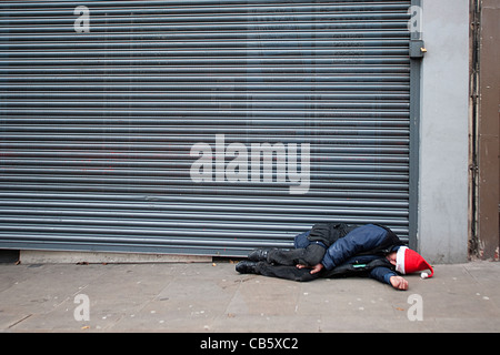 Senzatetto uomo dorme Natale sulla strada Foto Stock