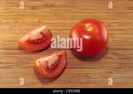 Pomodoro e due quarti di pomodoro su di un tagliere Foto Stock