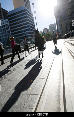 Ufficio a piedi i lavoratori a lavorare in città con lunghe ombre proiettate dalla bassa morning sun. Foto Stock