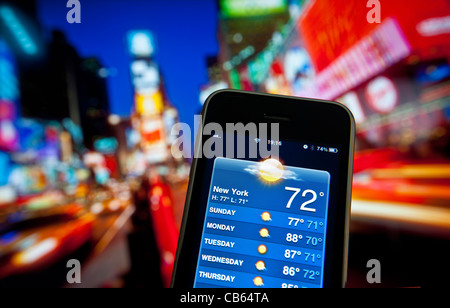 Times Square al crepuscolo con Apple iPhone con schermo di previsione app settimana di sole su meteo applicazione dello smartphone Foto Stock