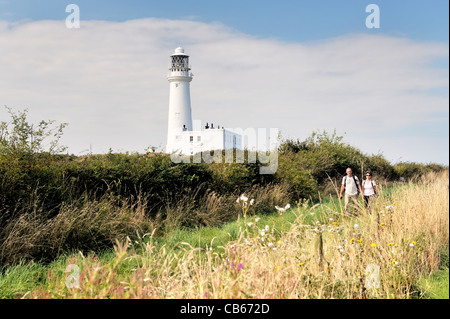 Flamborough Head Lighthouse sulla costa del Mare del Nord di East Yorkshire, Inghilterra, Regno Unito. Walkers sul sentiero. Estate Foto Stock
