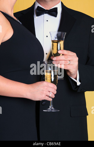 Foto di una coppia in black tie abito da sera con in mano un bicchiere di champagne. Foto Stock