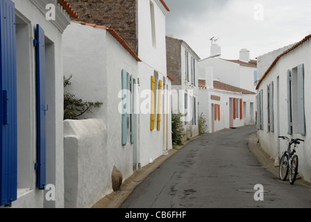 Small Alley con bianco-lavato le case colorate e i ciechi della finestra che conduce alla chiesa nel villaggio di Saint-Sauveur, IÎe d'Yeu Foto Stock