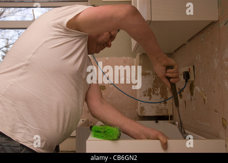 Tradesman utilizzando un martello per posizionare il piano di lavoro per la cucina nuova installazione in casa residenziale, Bordon, Hampshire, Regno Unito. Foto Stock