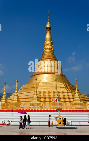 Oro gigante stupa di Tachileik Shwe Dagon Pagoda in Myanmar luccicante al sole con la gente che camminava da & a pregare nel santuario Foto Stock