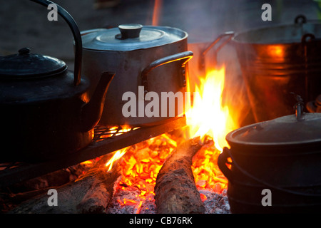 Acqua bollente nel bollitore e la cottura del cibo in vasi di metallo sul fuoco di legno aperto, Okavango Delta, Botswana, Africa Foto Stock