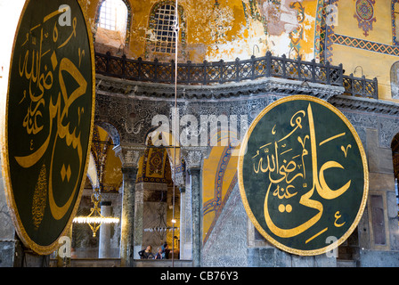 Turchia, Istanbul, Sultanahmet, Haghia Sophia Sightseeing di turisti nel nord galleria con coranici calligrafica islamica roundel Foto Stock