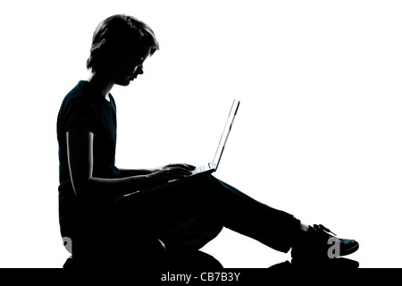 Un caucasian adolescente silhouette ragazza ragazzo di elaborazione del computer portatile a piena lunghezza in studio di ritagliare isolati su sfondo bianco Foto Stock