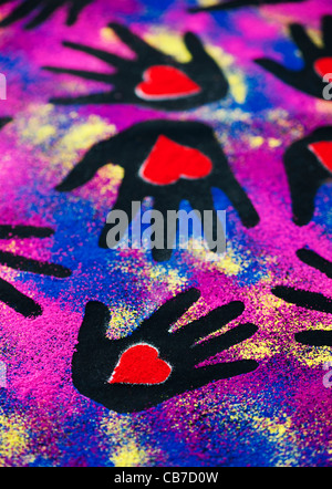 Childs stampe a mano con cuore rosso forme realizzata con polvere colorata su sfondo nero Foto Stock