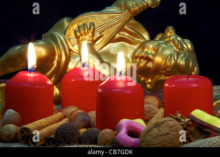 Corona di avvento con tre candele accese e un Angelo dorato in background Foto Stock