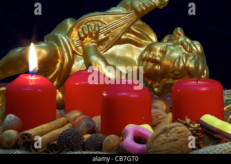 Corona di avvento con candele accese e un Angelo dorato in background Foto Stock