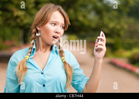 Giovane e bella ragazza dello studente con zaino in piedi nel parco del campus, con libri, sorridente e guardando nella telecamera Foto Stock