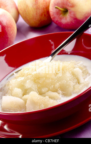 Salsa di mele con latte fresco in una ciotola rossa Foto Stock