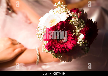 Un giovane damigella è azienda Bouquet nozze nelle sue mani. Foto Stock