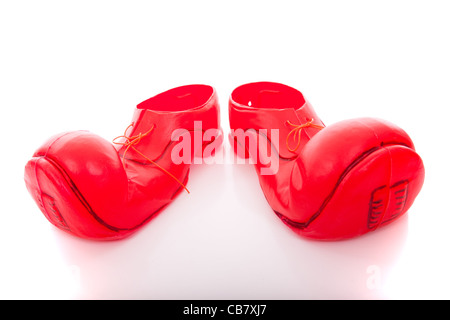 Piccole gambe del bambino all'interno di una coppia di grandi clown scarpe (isolato su bianco) Foto Stock