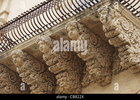 Balcone con angeli e facce, Noto, Sicilia Foto Stock