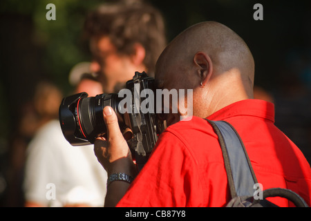 Un Uomo in camicia rossa riprese fotografiche professionali con fotocamera reflex digitale. Berlino, Germania. Foto Stock