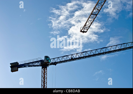 Sagome di gru edili contro un cielo blu Foto Stock