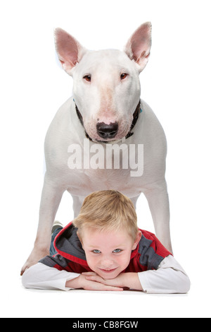 Un ragazzino sdraiato sul pavimento con il suo cane in piedi sopra di lui Foto Stock