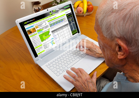 Anziano gentiluomo navigare il web controllo del meteo su un computer portatile Foto Stock